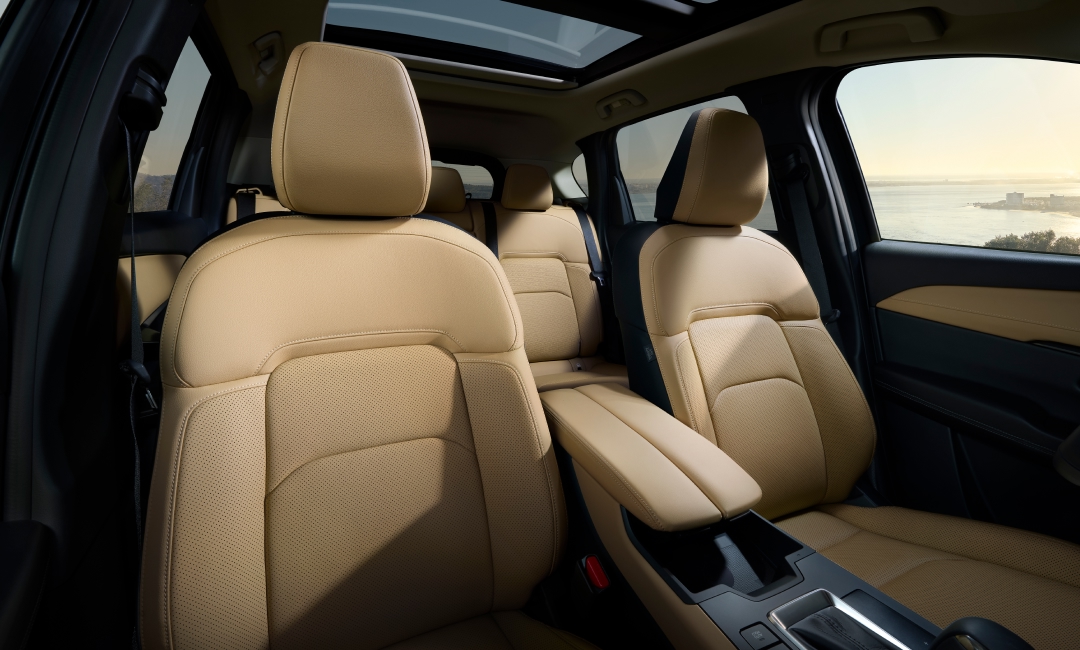 2026 Mazda CX-5 interior with beige leather seats, center console, and panoramic sunroof—luxury SUV cabin with scenic coastal view through windows.